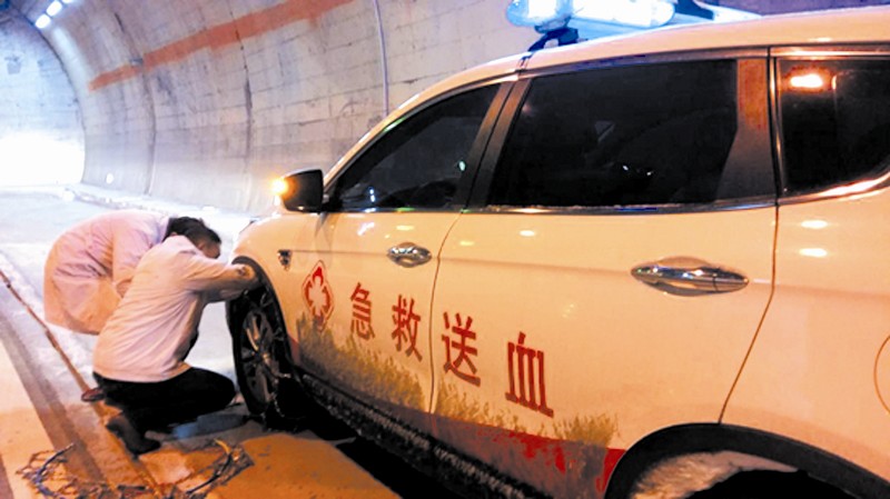市中心血站的工作人员为送血车安装防滑链.