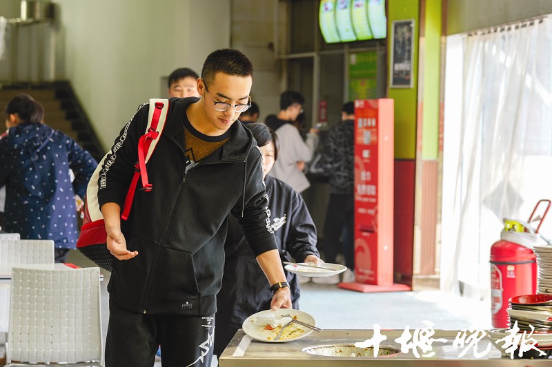 湖北医药学院食堂,就餐学生吃光饭菜后将餐具送到餐具收纳处.